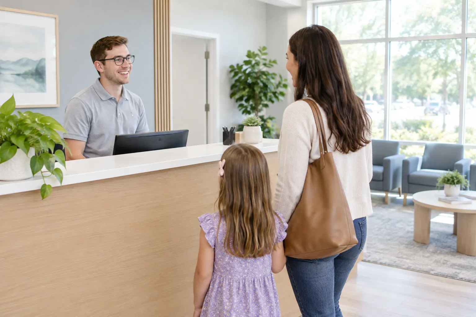 A receptionist greeting a mother and daughter at the front desk